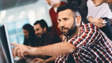 Grupo de pessoas em um escritório colaborando em um projeto no computador.