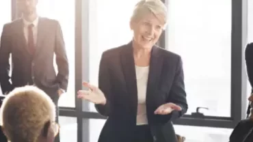 Mulher apresentando em reunião com equipe atenta.